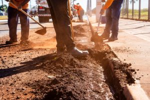Microtrenching machine cutting a narrow slot in pavement beside a directional drill rig